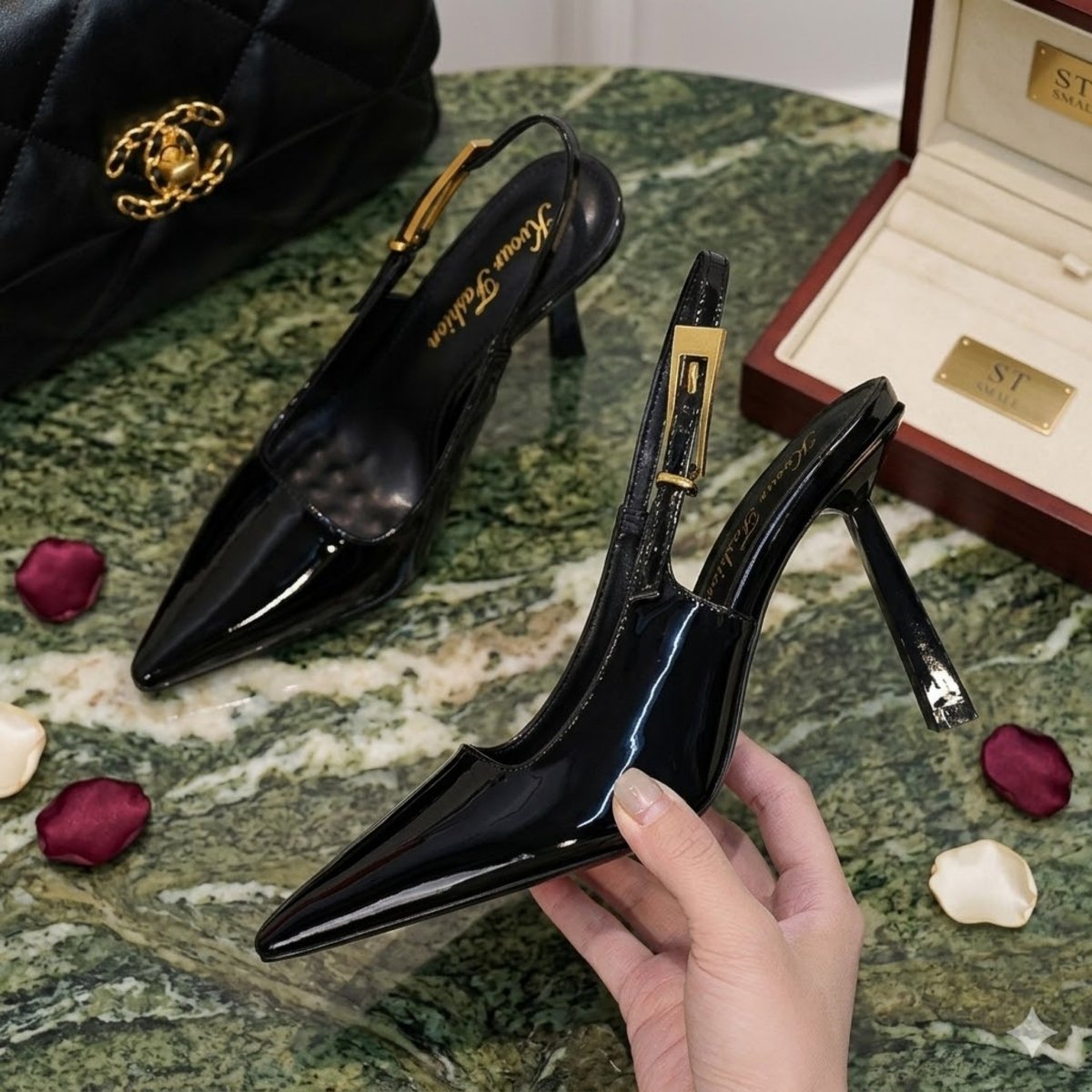 A pair of Kouvr Nyxara black croc-embossed leather slingback pumps with a stiletto heel resting on a luxury marble tabletop.