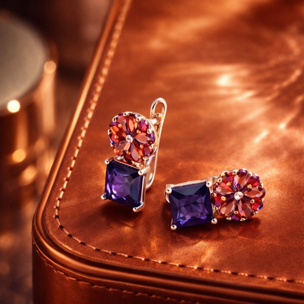 A close-up of the Kouvr Octivia floral drop earrings on a brown leather case, highlighting the gemstone details.
