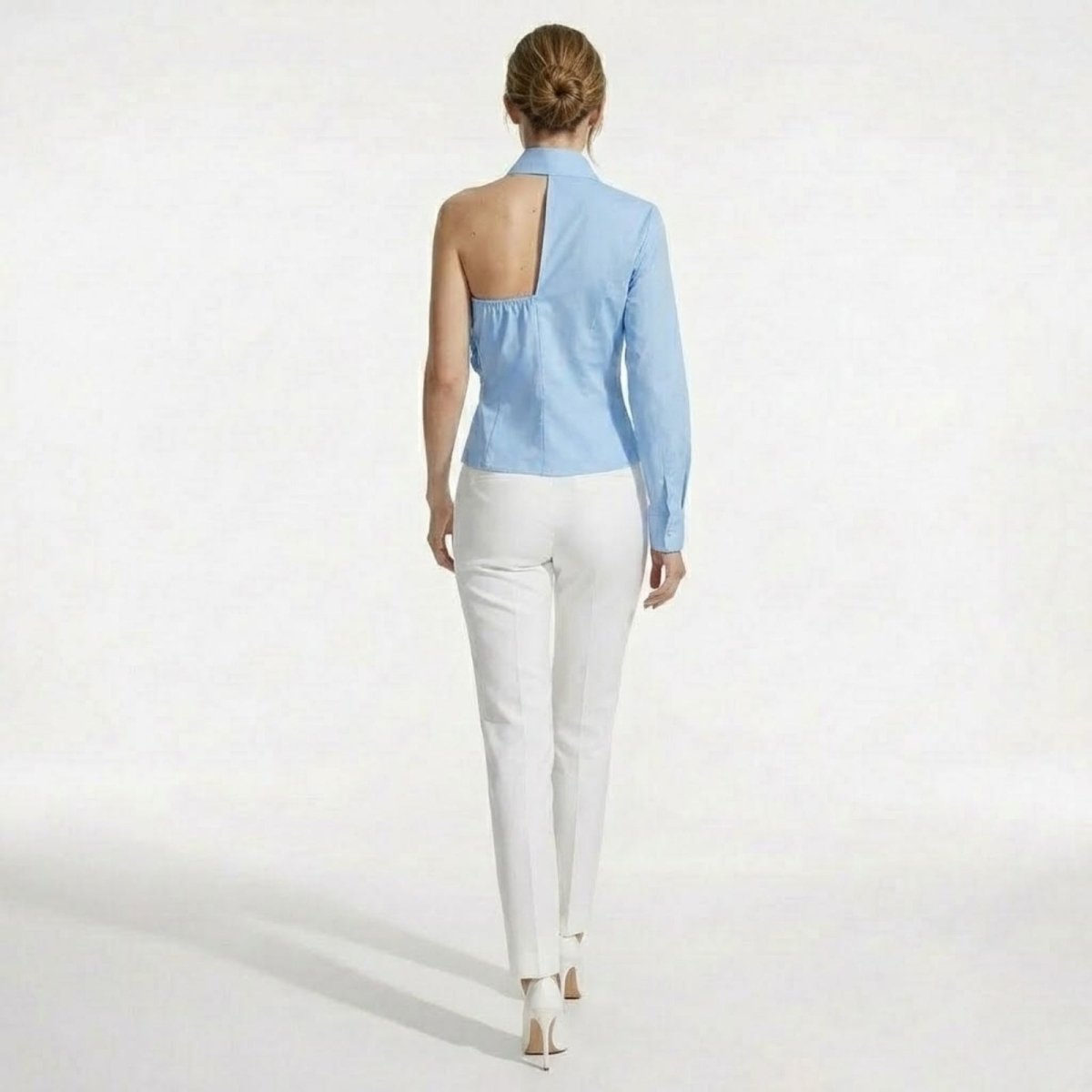 Back view of the Kouvr light blue blouse, highlighting the unique open-back cutout and asymmetrical design.
