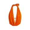 Model wearing Kouvr's Rosette featuring an orange sequin backless halter top
