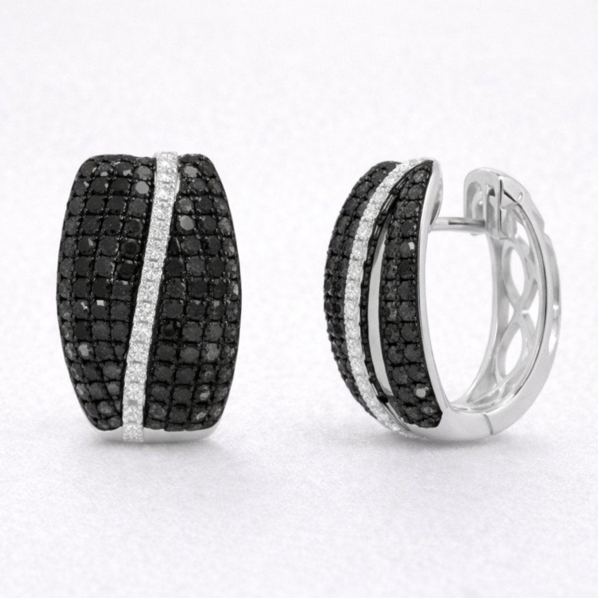 A pair of Kouvr statement huggie earrings with pave black and white diamonds in 14K white gold on a clean white background.
