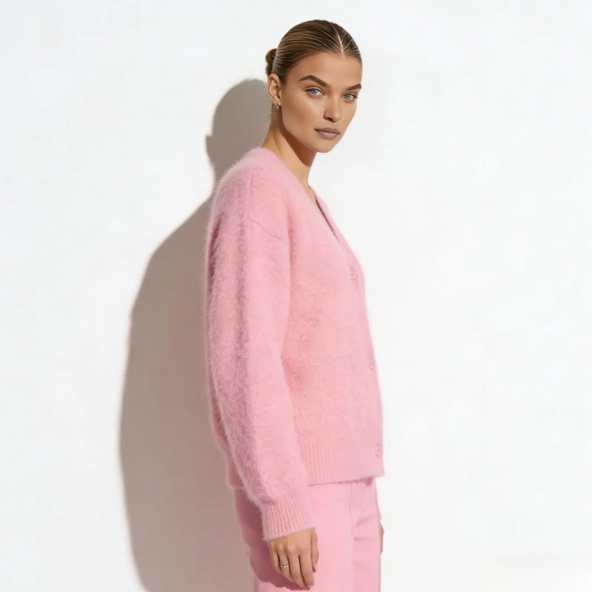 Side profile of a model wearing the Kouvr soft pink relaxed fit mohair blend cardigan showing its texture.