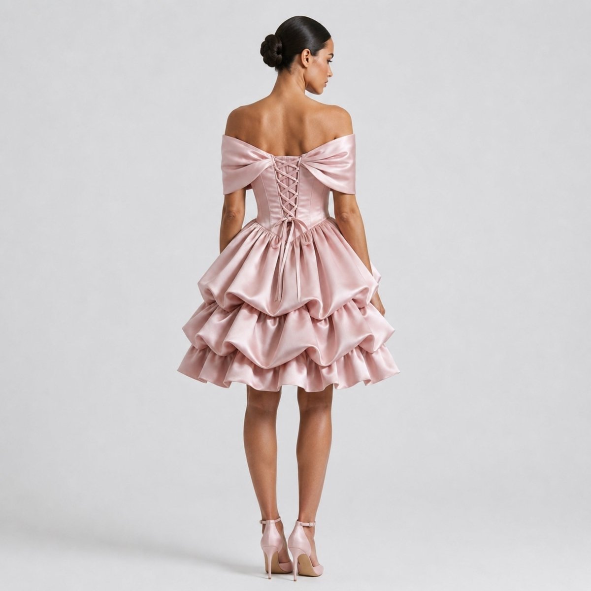 Back view of Kouvr pink satin mini dress highlighting adjustable lace-up corset back closure and shoulder drape.