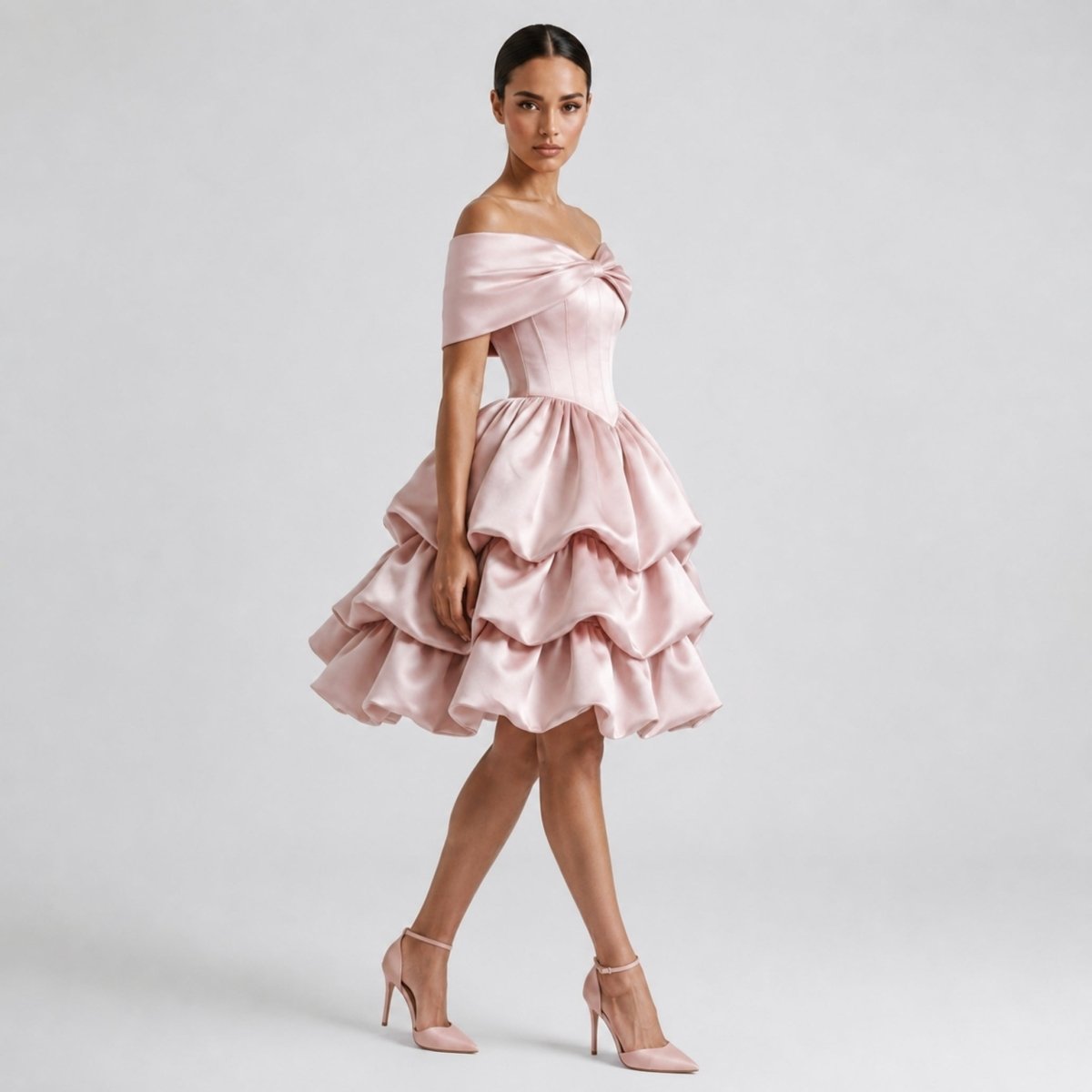Side profile of woman in Kouvr pink satin off the shoulder party dress showing voluminous tiered skirt and bow detail.