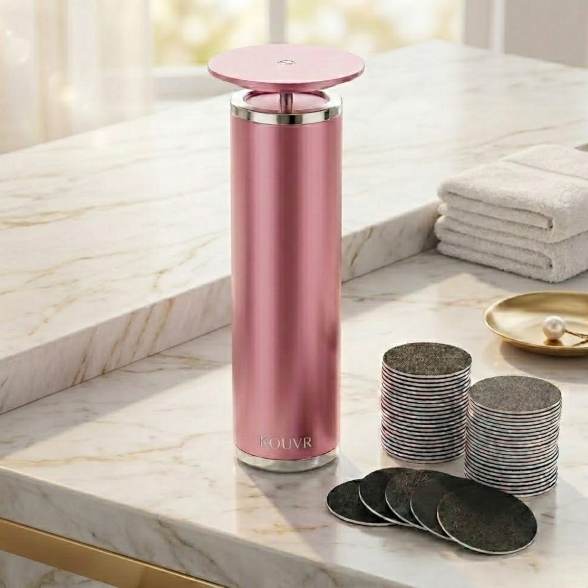 Kouvr professional electric foot callus remover in rose gold on a marble vanity with 60 replacement sanding discs
