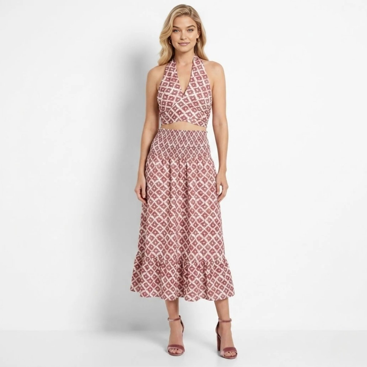 Model wearing Kouvr red geometric print halter crop top and smocked midi skirt two piece set facing forward.