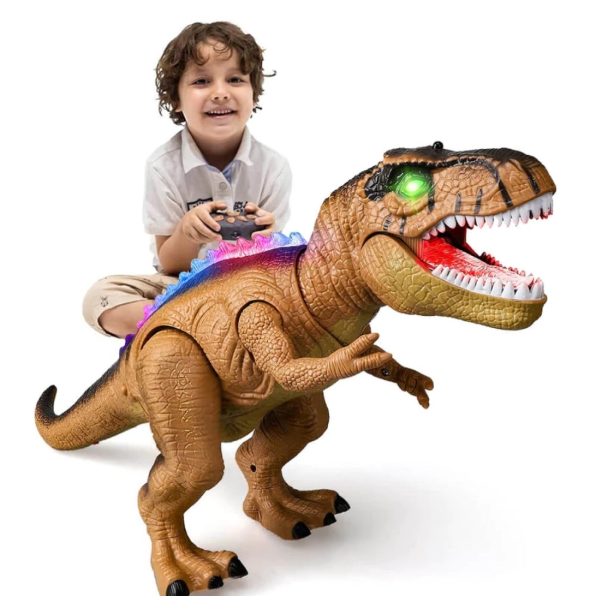 A happy young boy sits and plays with the brown Kouvr remote control T-Rex dinosaur toy that features glowing green eyes and rainbow LED back spines.