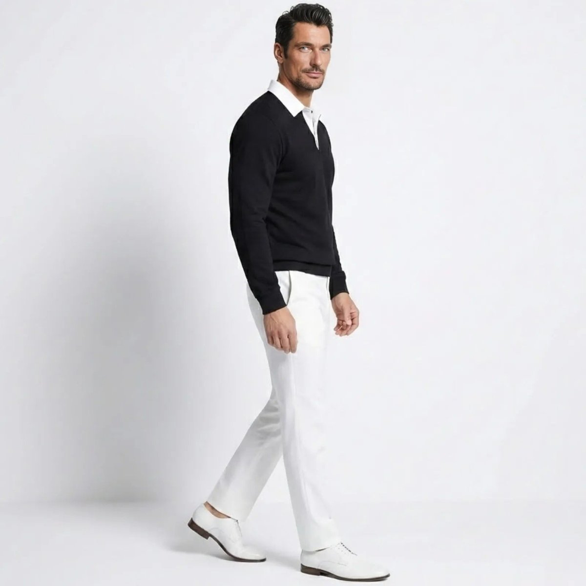 Side view of a male model walking in the Kouvr Rhodes  black long sleeve polo sweater, showing the classic fit and drape of the merino-cashmere fabric.