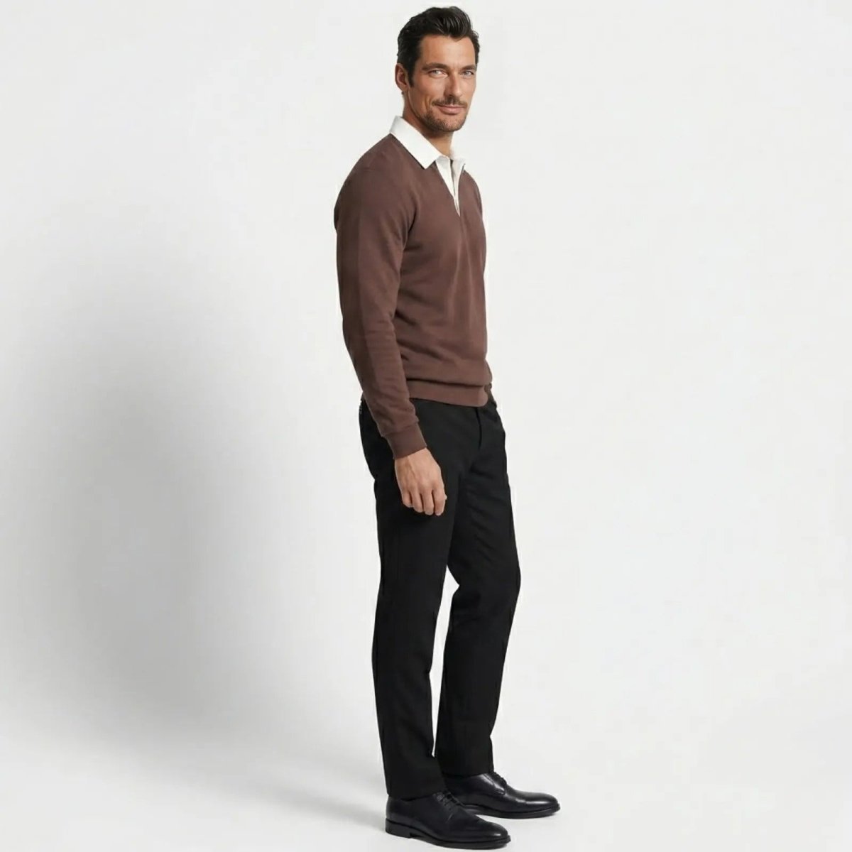 Side profile of a man in a Kouvr dark brown knit polo sweater showing the tailored fit and silhouette against a white background.