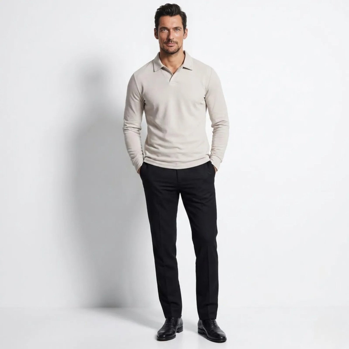Man wearing the Kouvr Rome long sleeve knit polo in cream with black trousers, front view.
