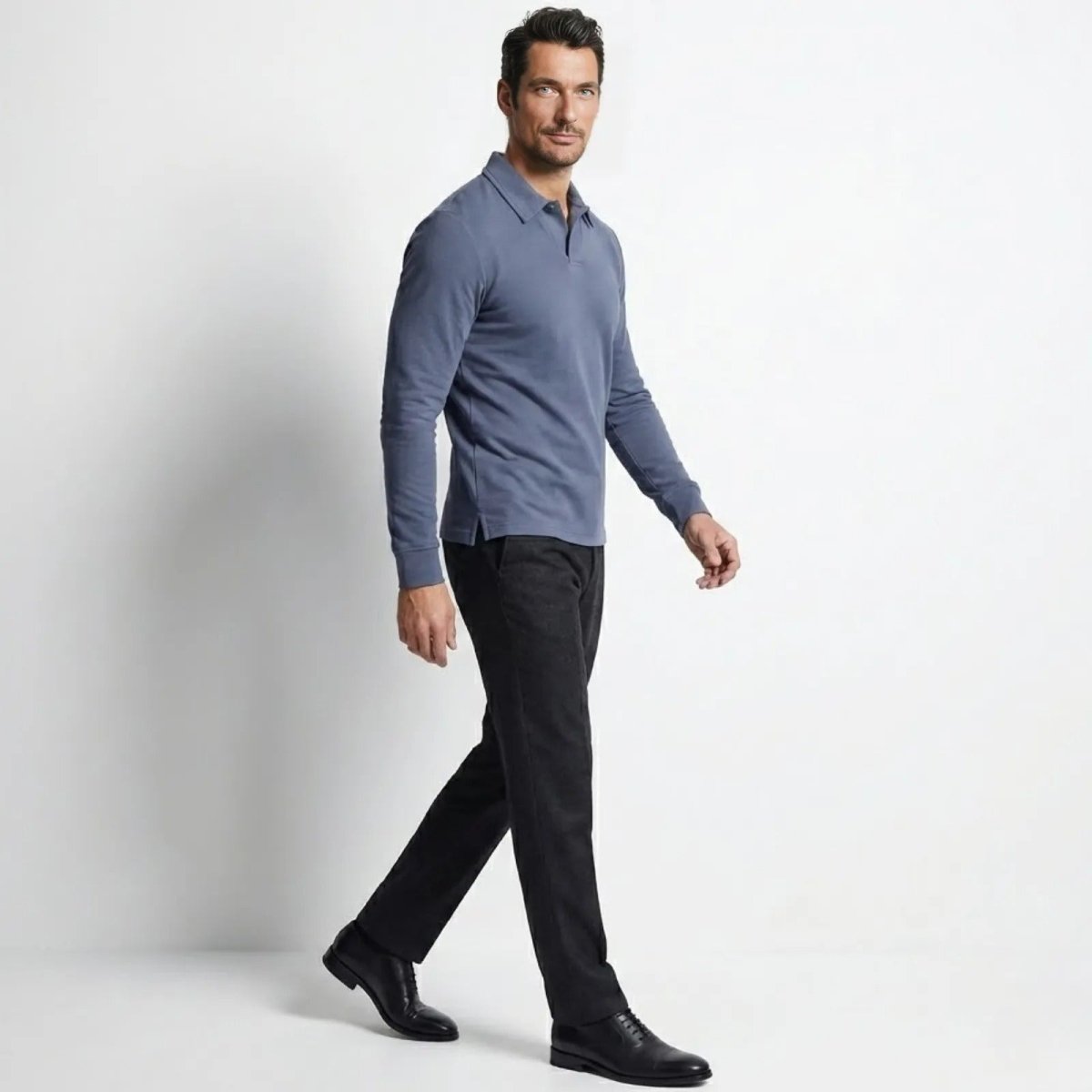 Man in a walking pose wearing the Kouvr Rome Long Sleeve Polo in slate blue, showing the side profile and drape of the shirt.