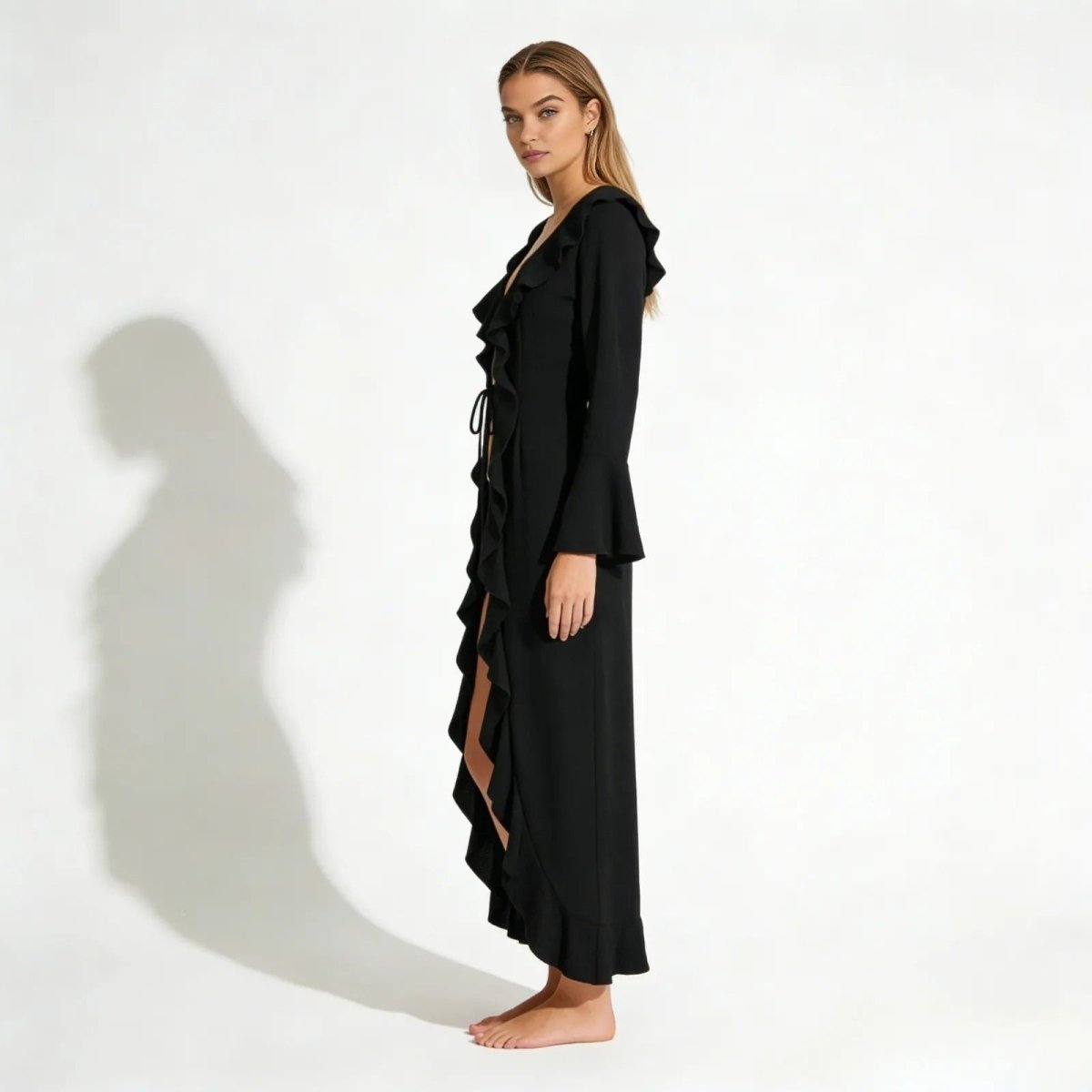 Side profile of a model in the Kouvr Fashion Roseta black maxi robe, highlighting the flared bell sleeves and flowing silhouette.