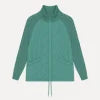 Model wearing Kouvr sage green quilted jacket with cable knit sleeves, viewed from the front