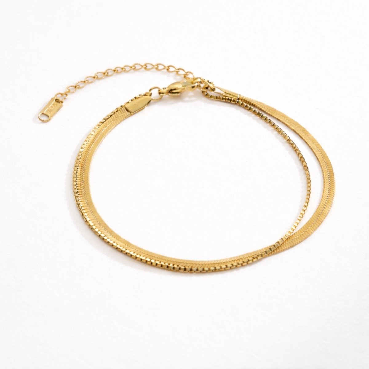 The Sarielyn layered gold anklet by Kouvr, featuring a herringbone and box chain, on a clean white background.