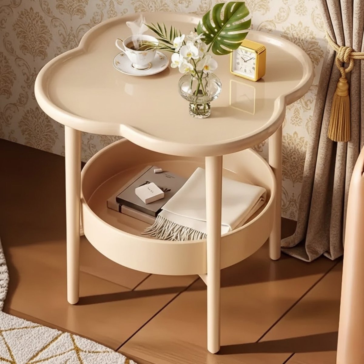 A sage green Kouvr clover-shaped end table with two tiers, placed on a decorative rug in a bright, luxurious room setting.