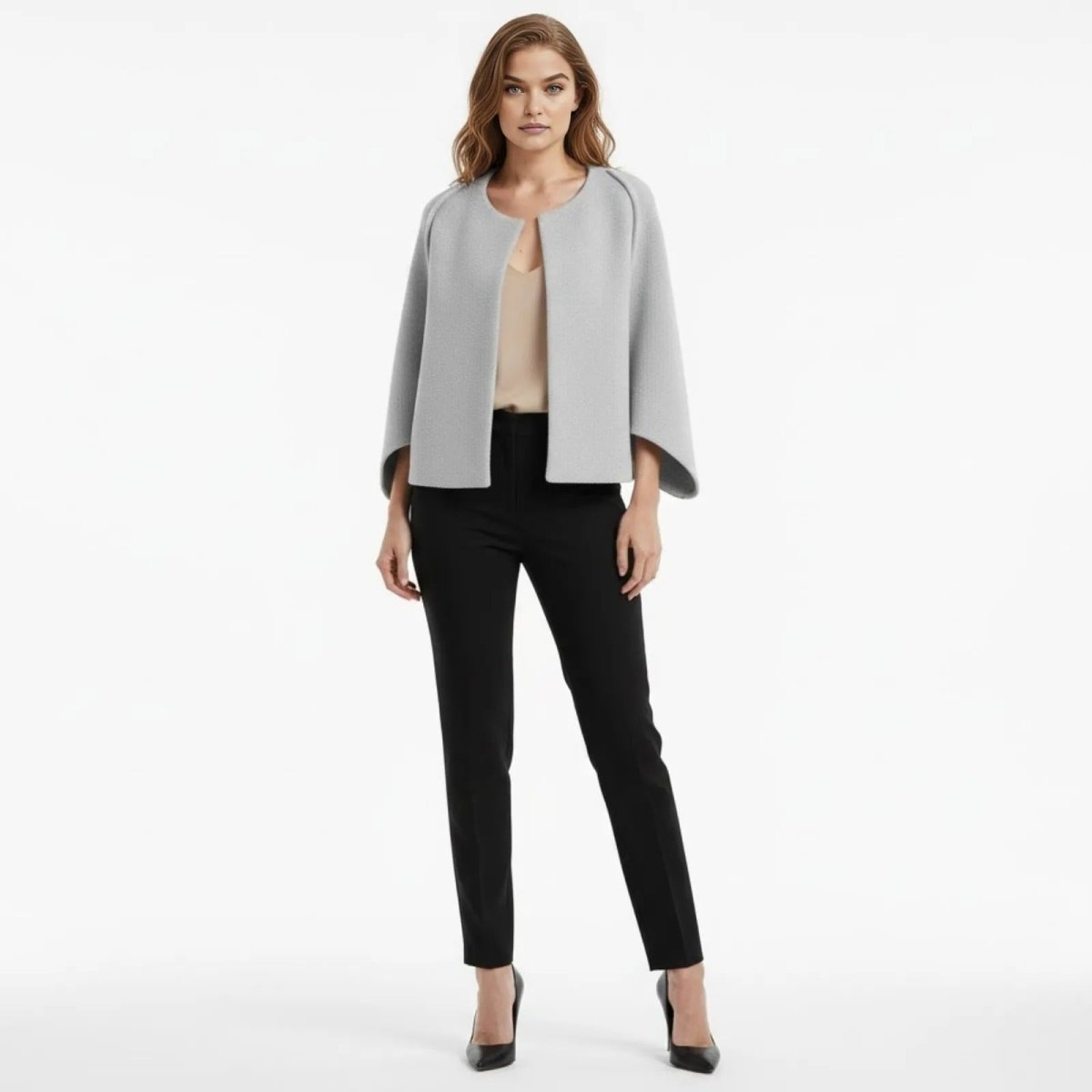 Model wearing the Kouvr light grey sculptural cape jacket with black trousers, front view.
