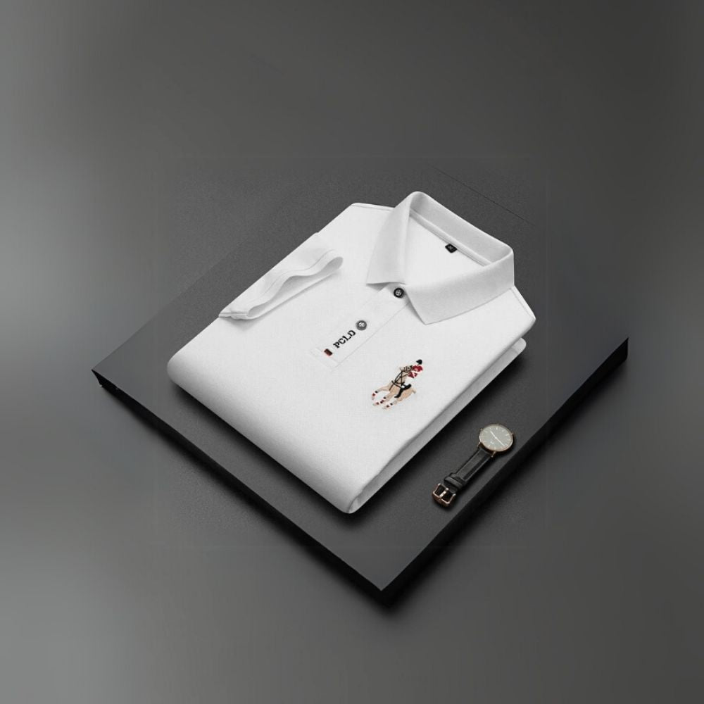 White kouvr polo shirt with a small design on a black surface