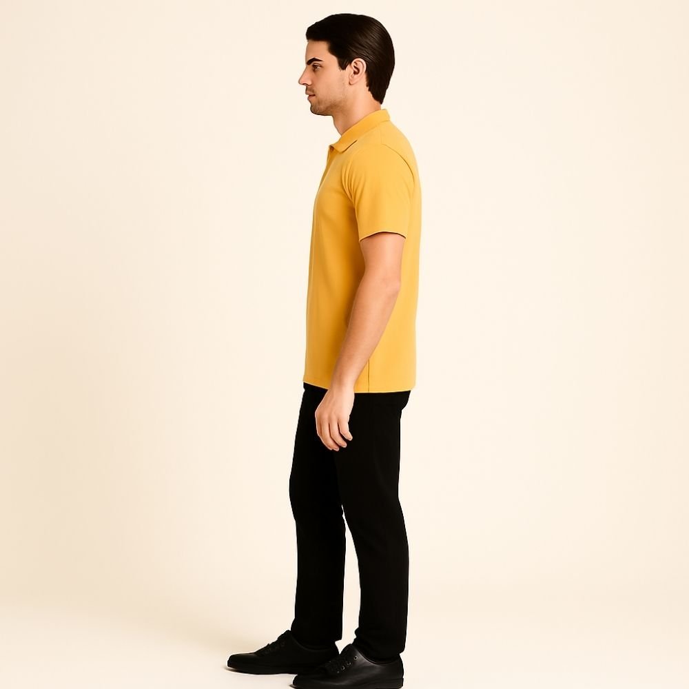 Man wearing a yellow kouvr polo shirt and black pants on a beige background