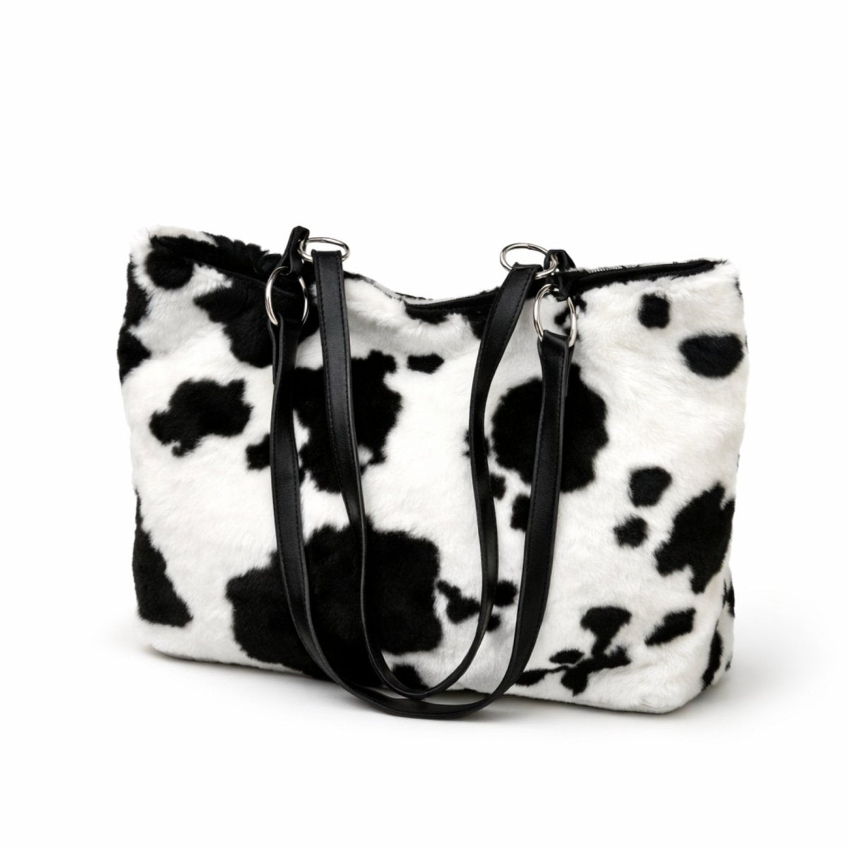 The Kouvr Soroya Tote Bag in a plush black and white cow print faux fur with black vegan leather straps, shown on a white background.
