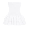 Model wearing the Kouvr Starla white strapless smocked mini dress with a tiered broderie anglaise ruffle skirt