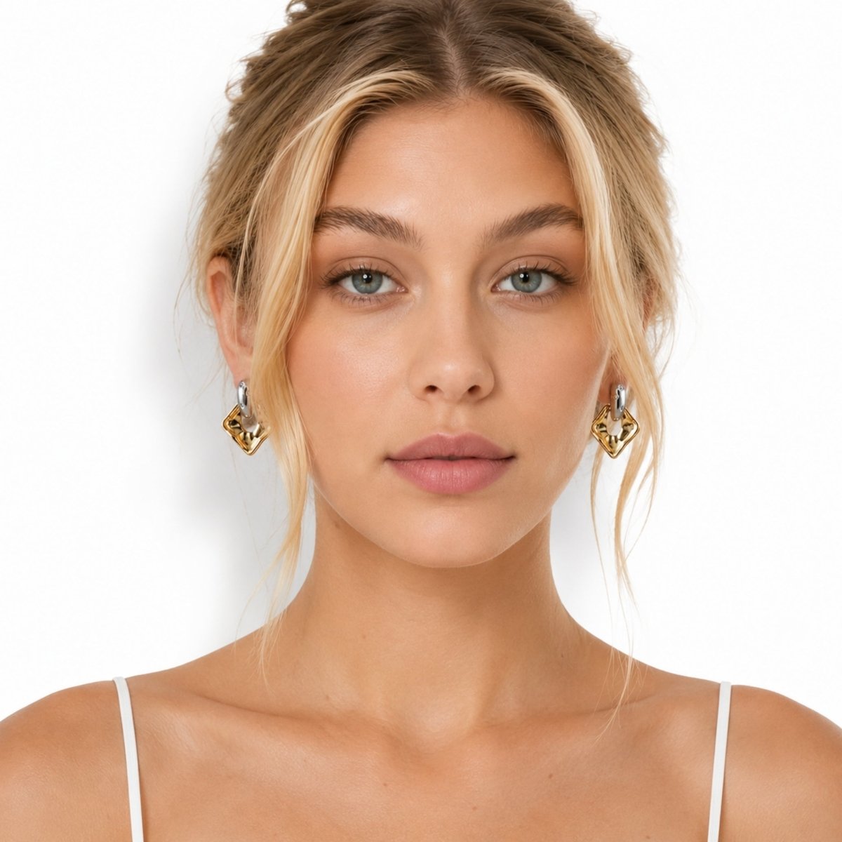 Close up portrait of a female model wearing Kouvr modern gold and silver geometric dangle earrings framing her face.