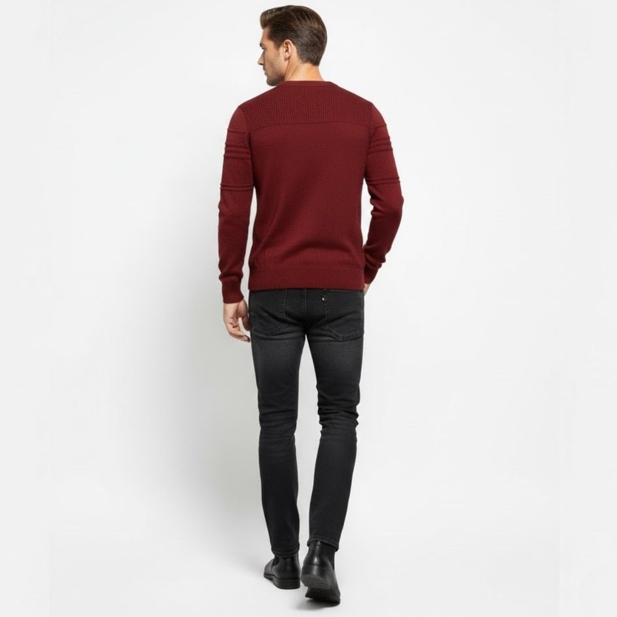 Back view of a male model walking away wearing the Kouvr red textured crewneck sweater and slim-fit black jeans.
