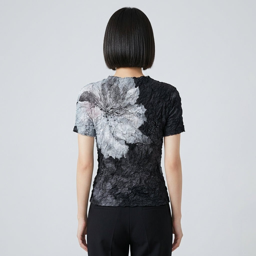 Back view of the Kouvr crinkled black statement blouse showing the wrap-around grey floral print.