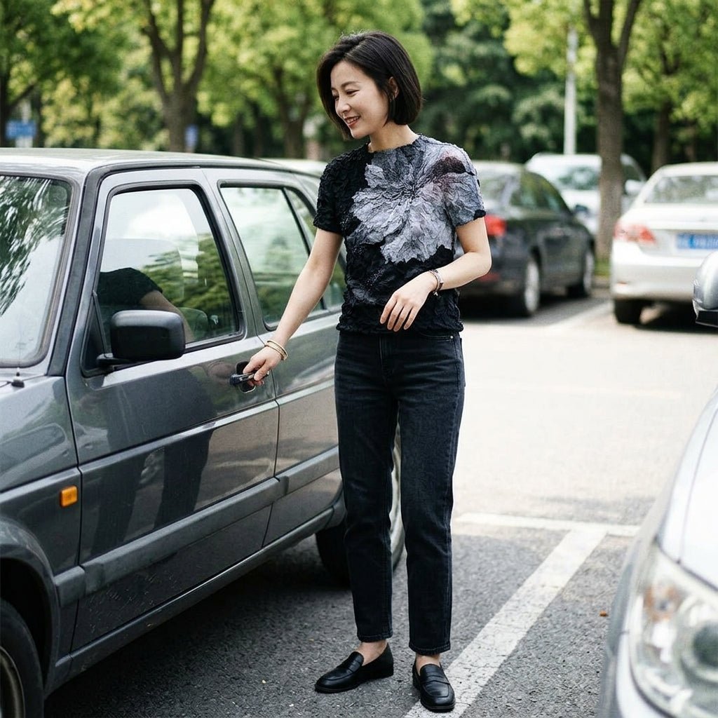 Lifestyle fashion shot of a smiling woman wearing the Kouvr textured floral top with black jeans getting into a car.