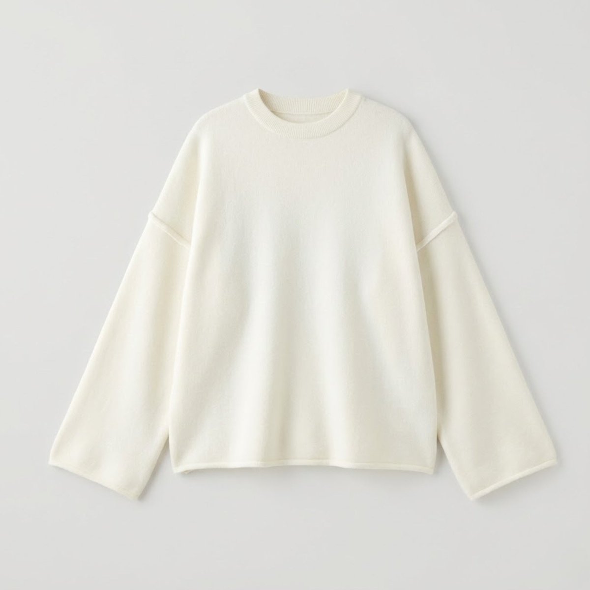 Flat lay of the Kouvr Krystal sweater in ivory, displaying the mock neckline, external seams, and luxurious soft knit texture on a white surface.