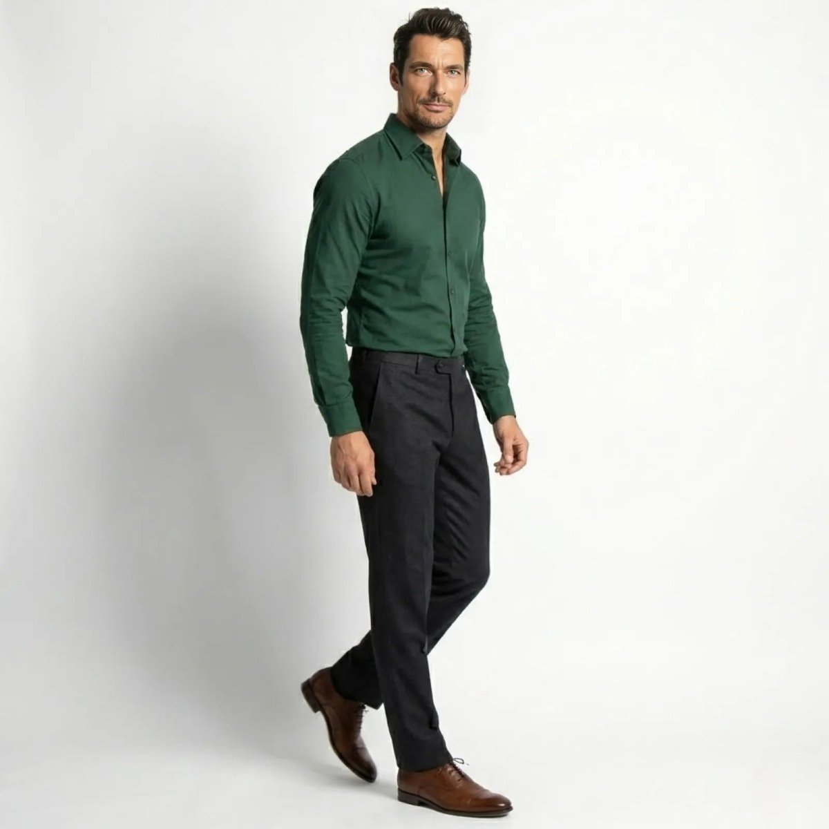 Side profile of a model walking in the Kouvr Leland dark green long sleeve shirt, showcasing its tailored fit and drape.