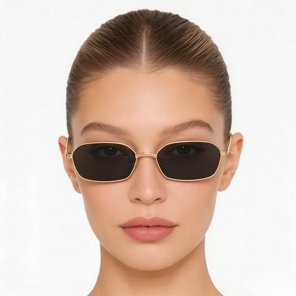 A woman wearing Kouvr's The Liezel gold hexagonal sunglasses, looking directly at the camera to show the frame's fit and style.
