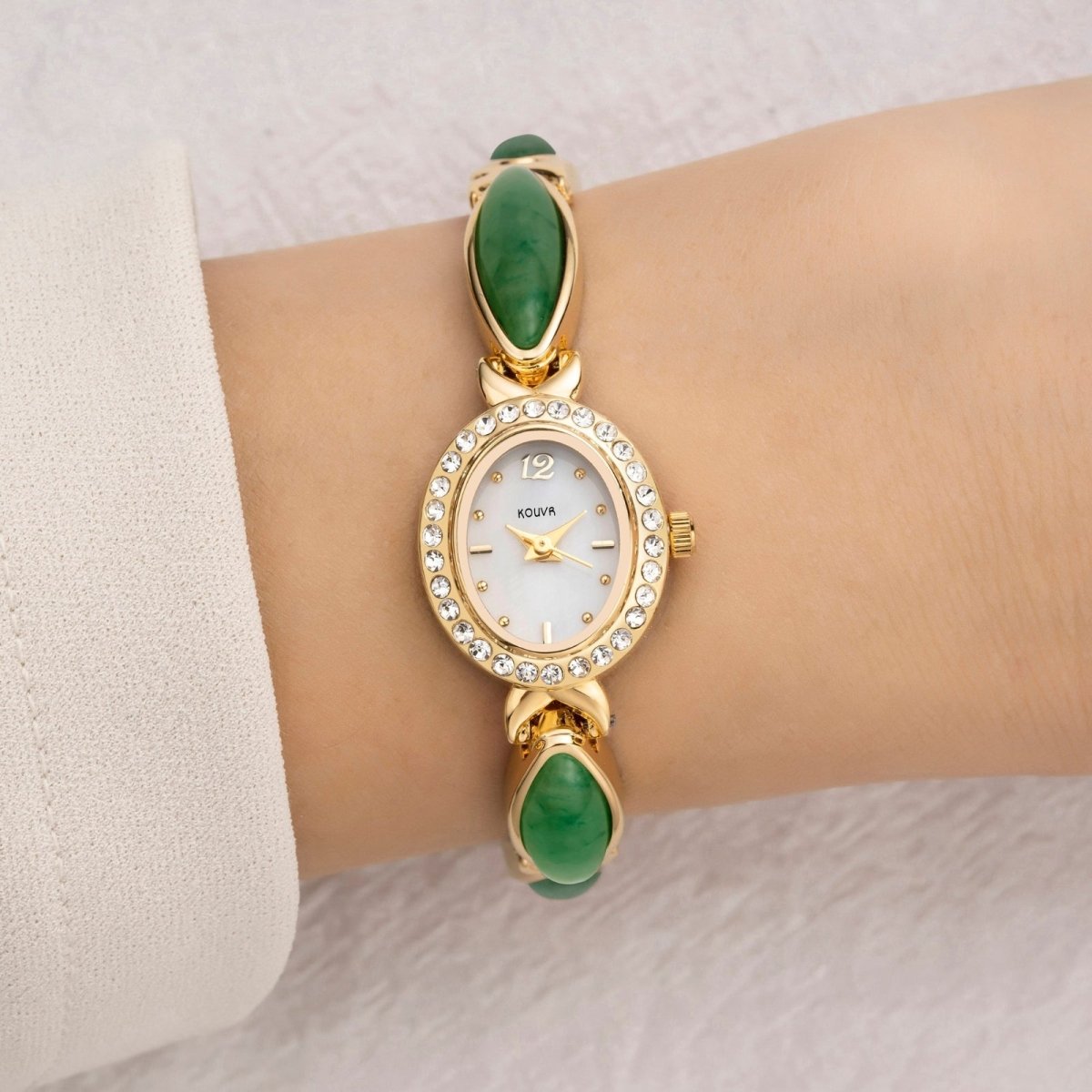 A woman wearing the elegant Kouvr Tiger's Eye and gold bracelet watch, paired with a white sleeve.