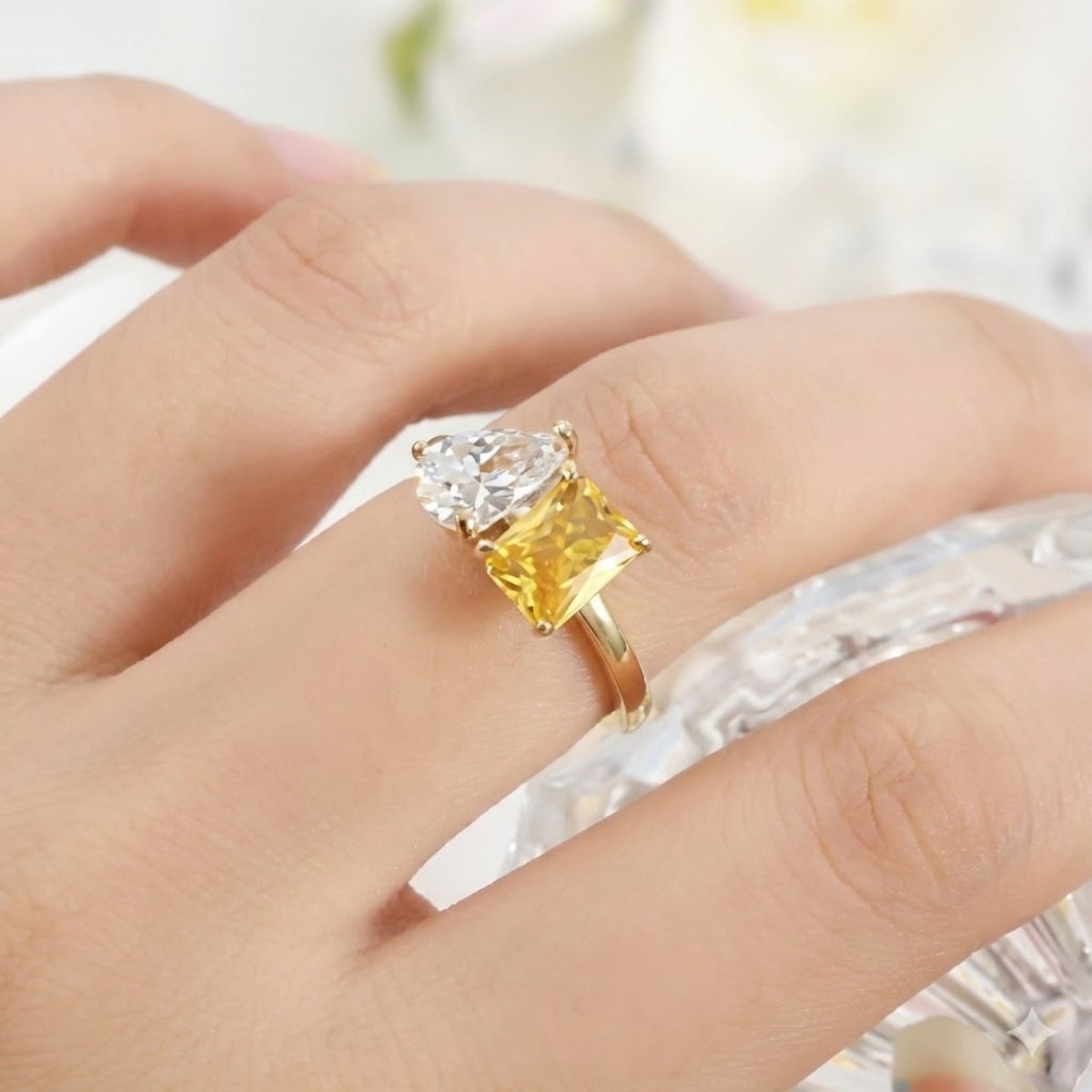 A close-up view of the Kouvr yellow and white two-stone ring on a woman's finger, highlighting the brilliance of the zircon stones.
