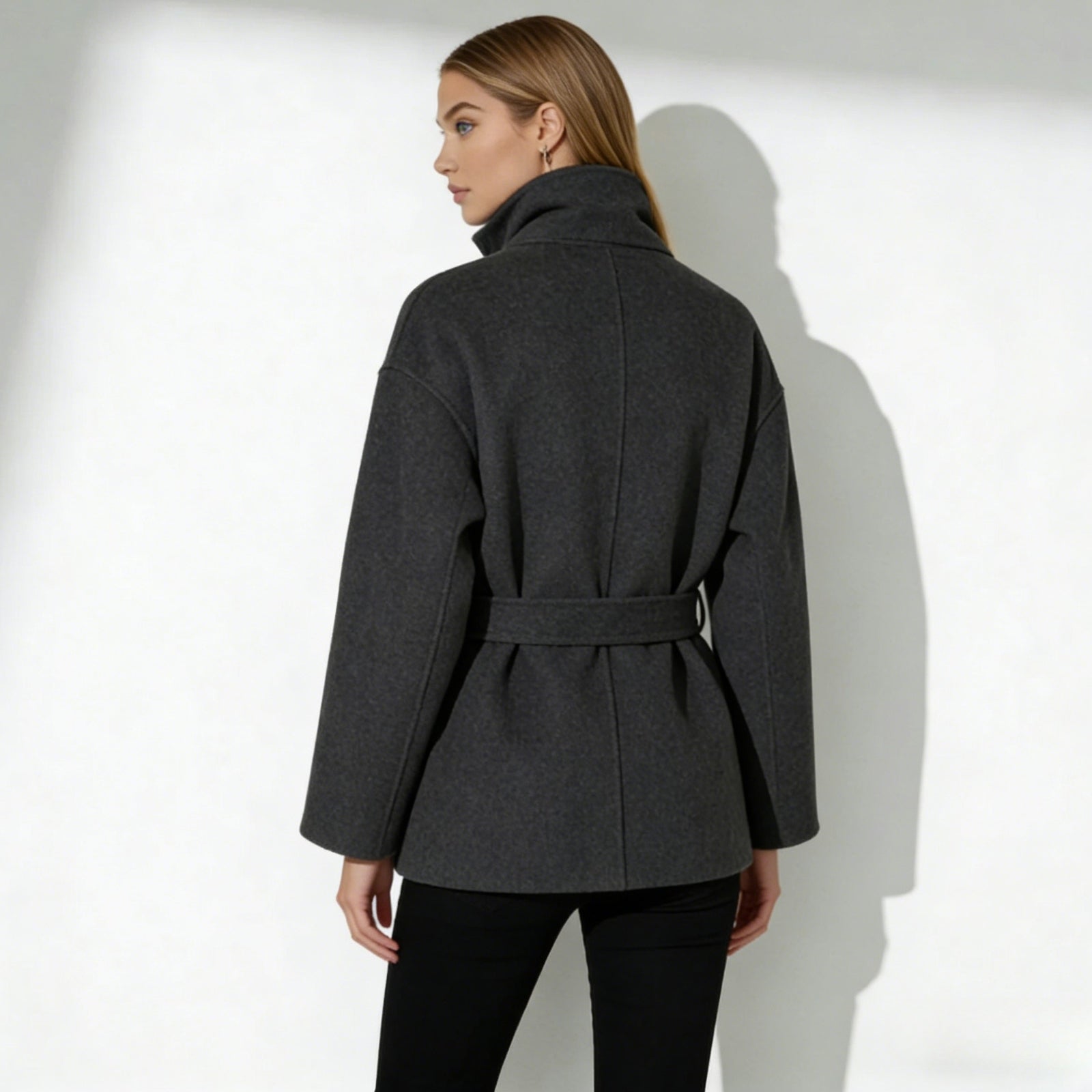 Back view of the Kouvr Verna belted wool coat in dark gray, highlighting the clean lines and belt detail.
