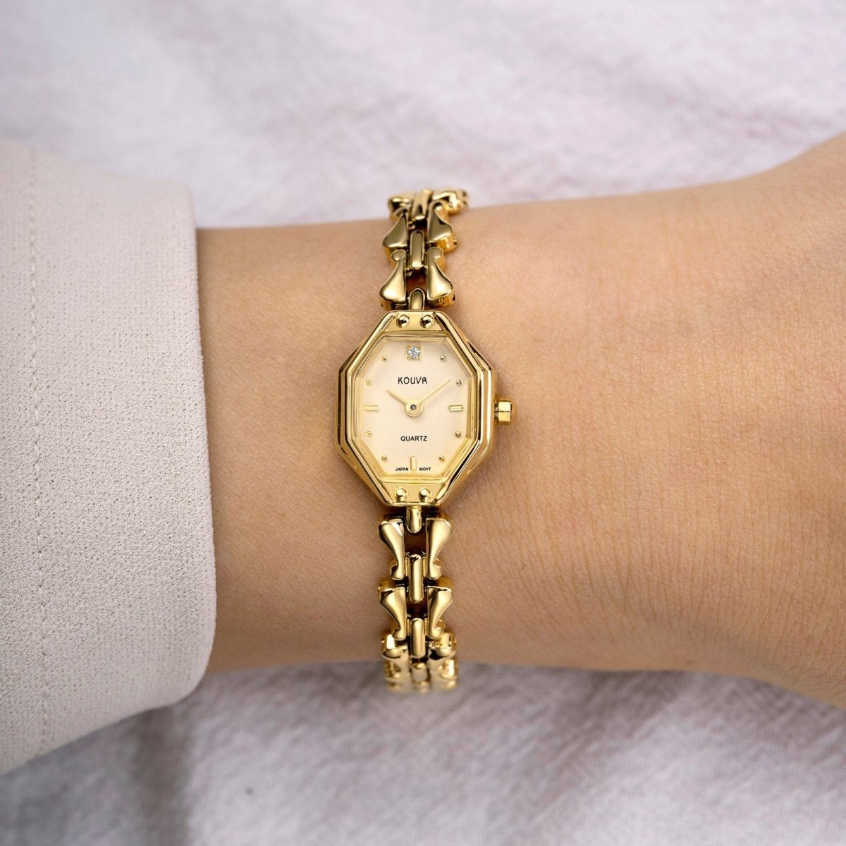 Gold kouvr  wristwatch with decorative band on a white background