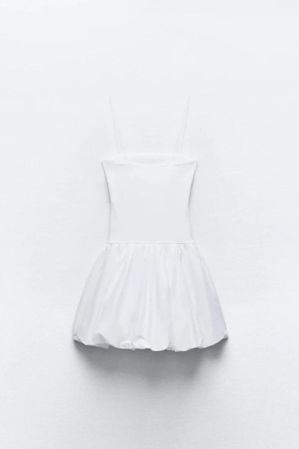 Model wearing the Kouvr white bubble hem mini dress with spaghetti straps