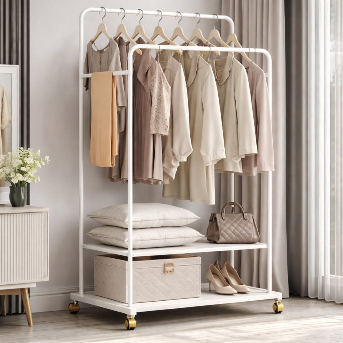The Kouvr white double rod garment rack with elegant gold casters, styled with beige and neutral clothing, pillows, a designer handbag, and heels.