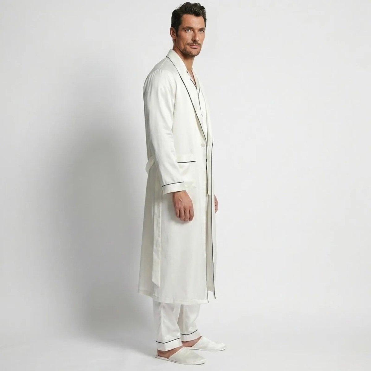 Side view of a model in the Kouvr Wilson Set white silk pajama set and robe with black piping, showing the relaxed fit.