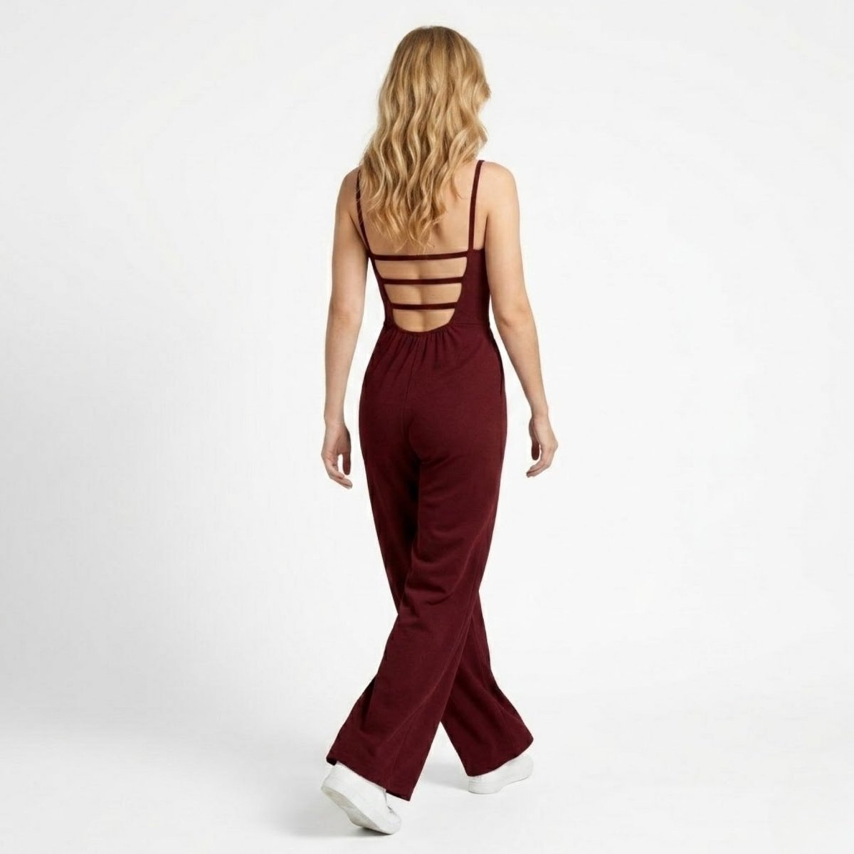 Back view of Kouvr wine red evening jumpsuit showcasing the architectural horizontal strappy open back detail.