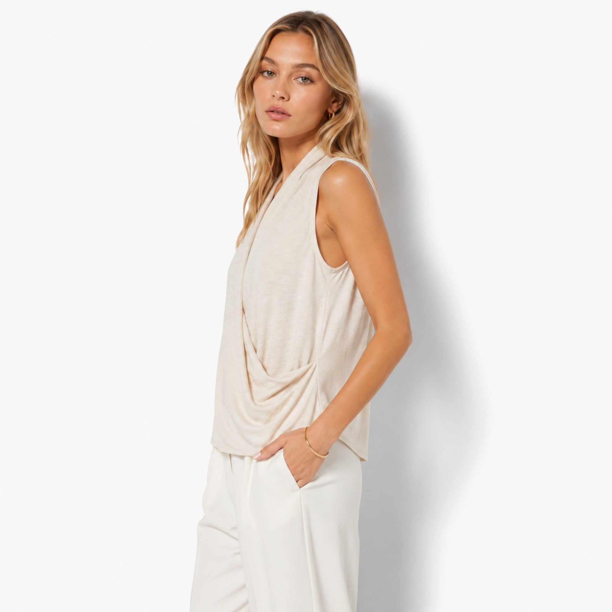 Side view of an elegant beige knit halter top demonstrating the architectural draped front styling, gathered waist detail, and relaxed fit by Kouvr