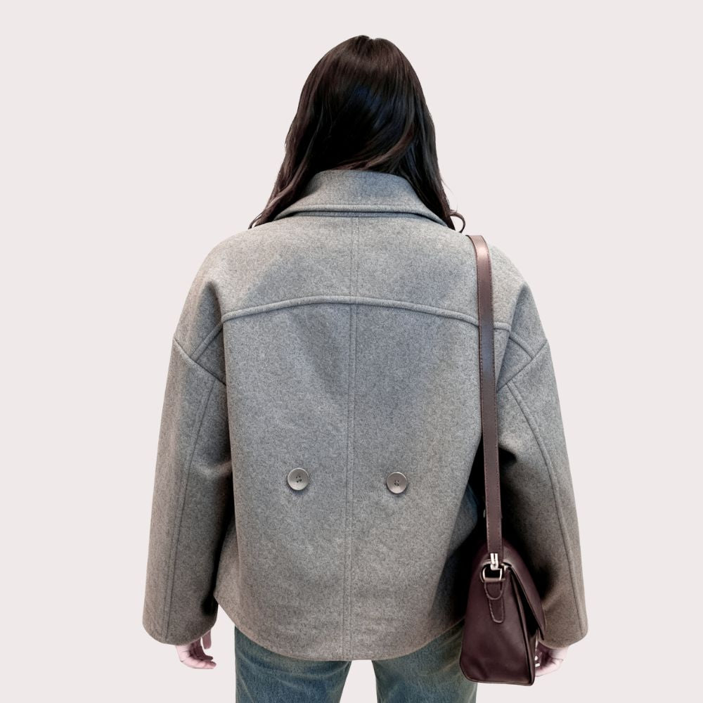 Woman wearing Kouvr's gray wool double-breasted peacoat with a white turtleneck