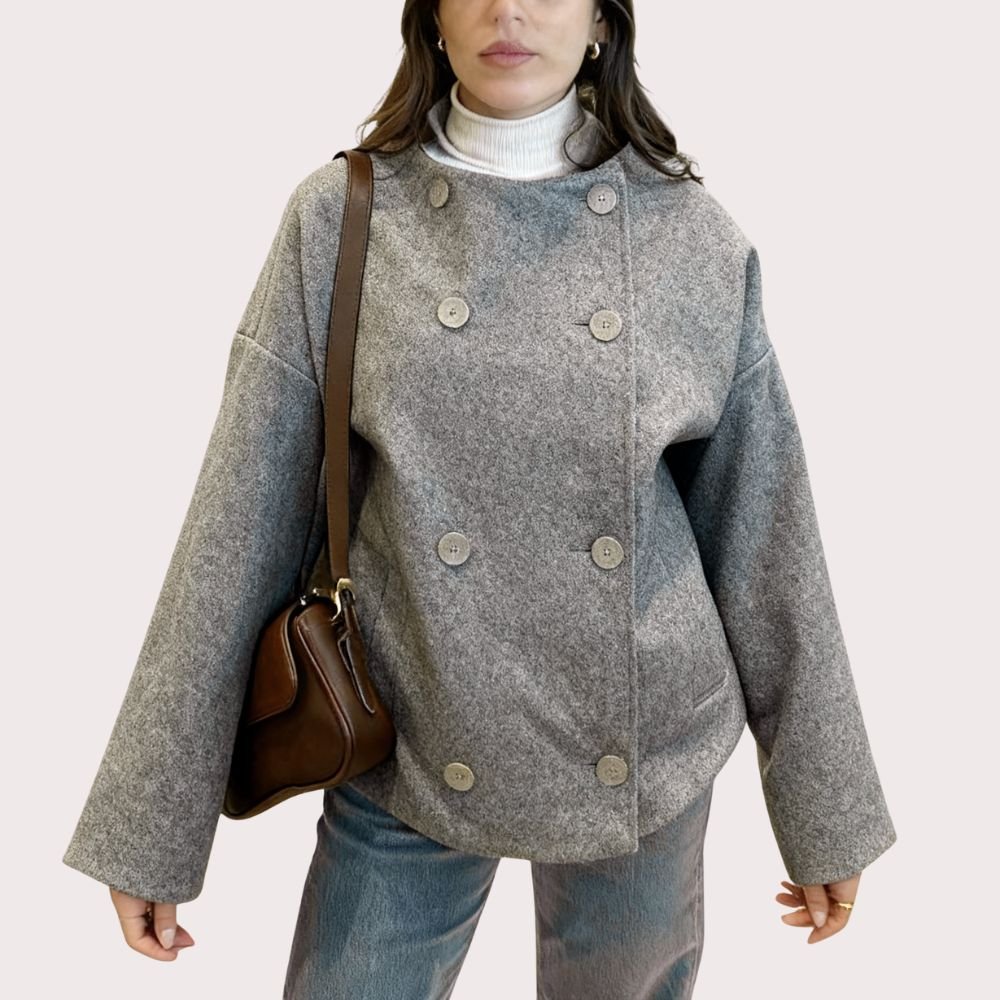 Woman wearing Kouvr's gray wool double-breasted peacoat with a white turtleneck