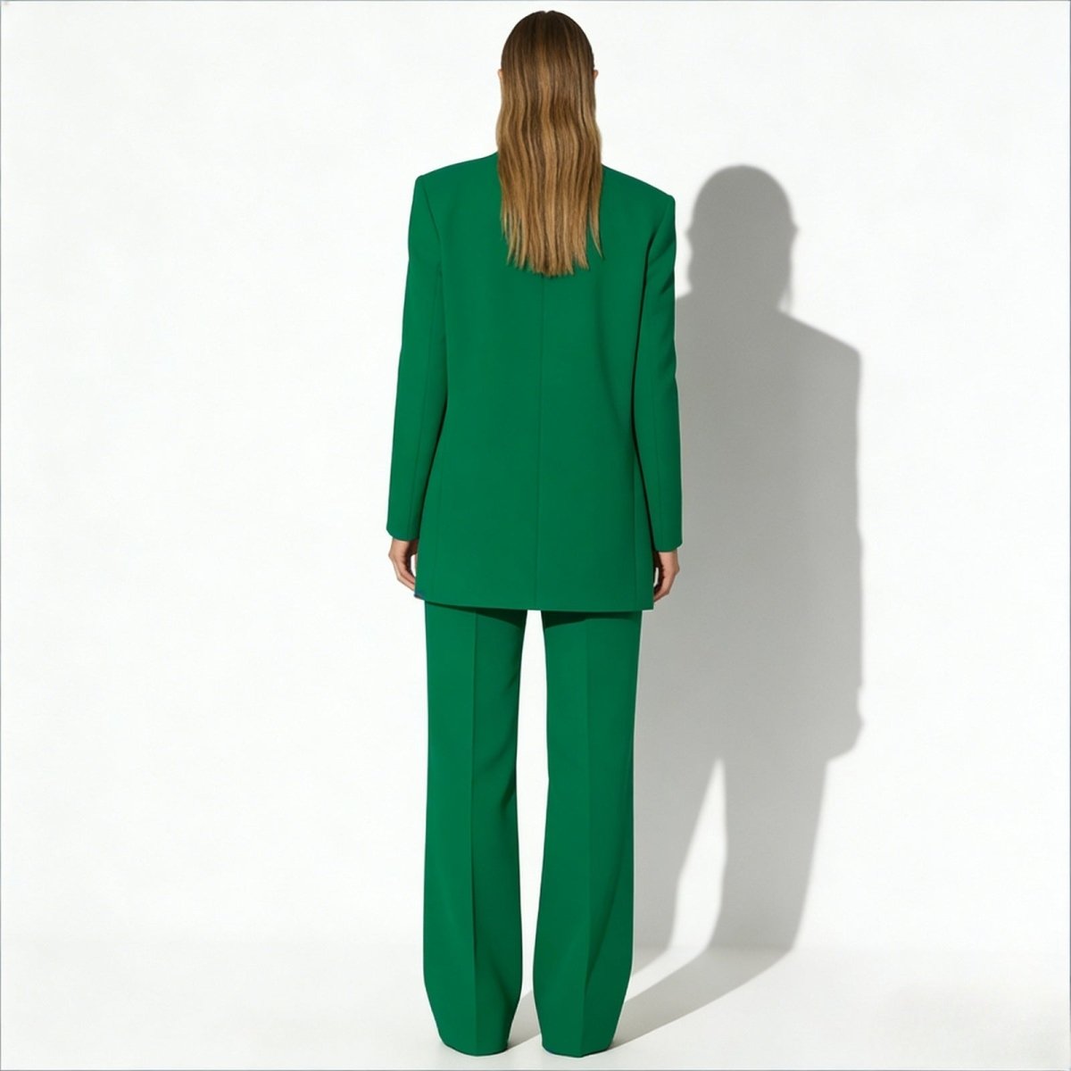 Rear view of a model wearing the Kouvr kate green suit, highlighting the clean lines and tailoring of the blazer's back panel.
