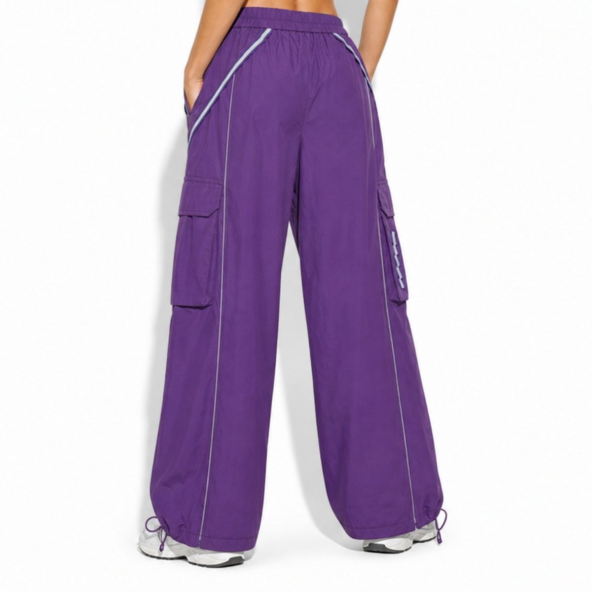Back view of women's baggy purple Y2K utility streetwear trousers highlighting relaxed wide-leg fit and rear elastic waistband design.