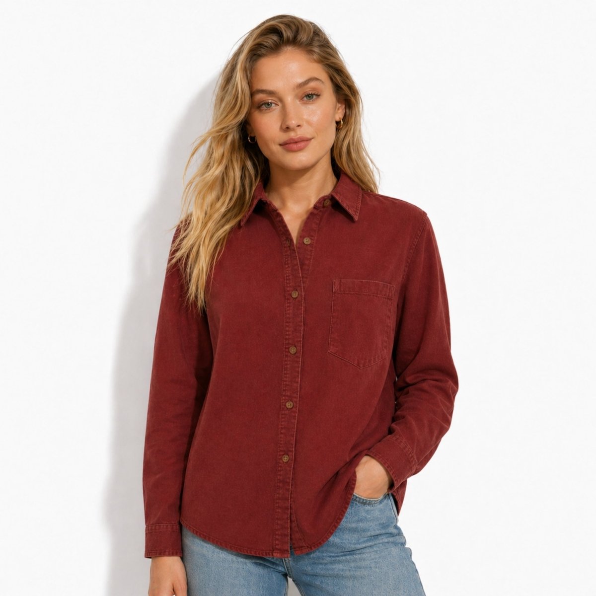 Woman modeling the Kouvr red brushed cotton button down shirt styled with light wash jeans, half tucked with hands in pockets.