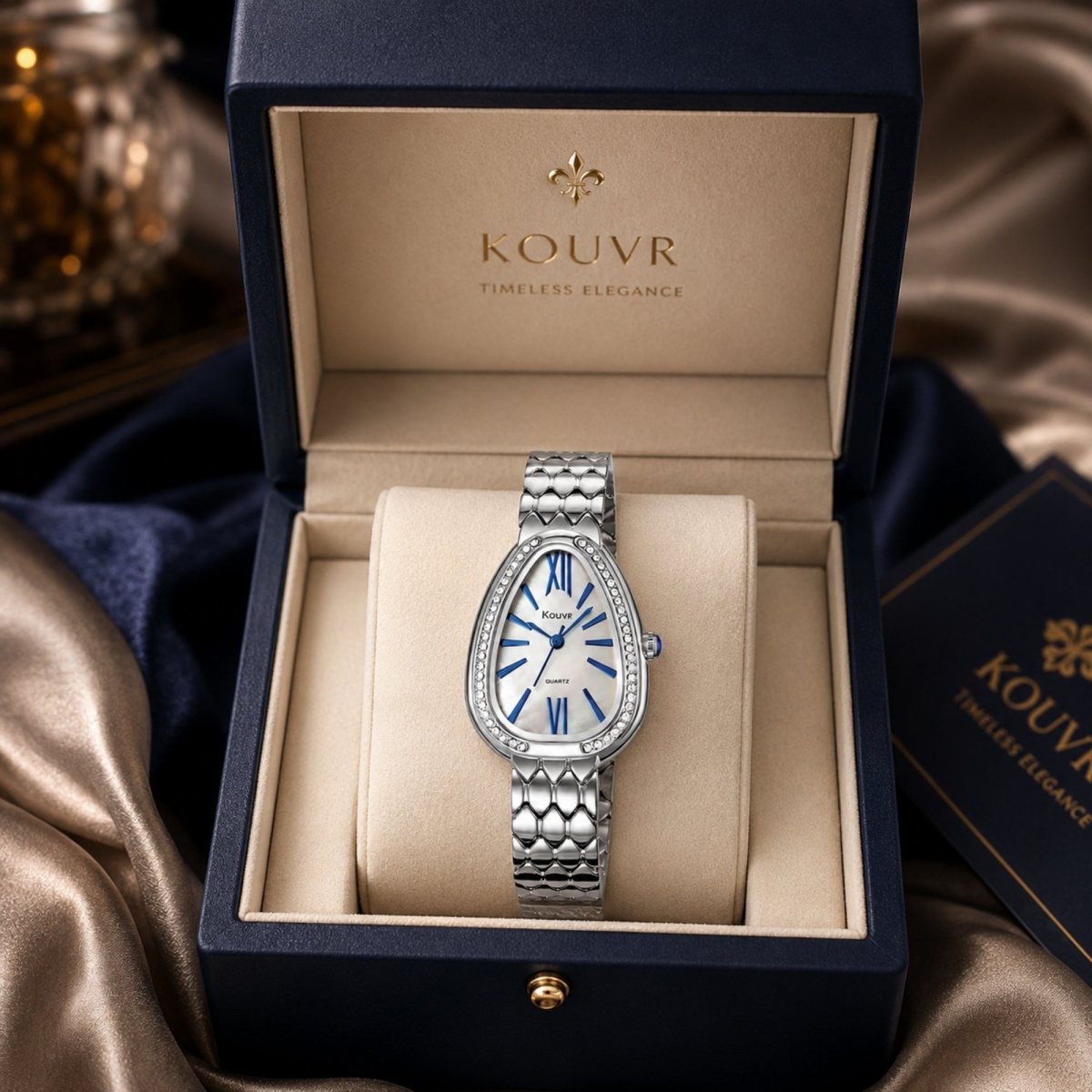 Close-up studio shot of Kouvr ladies silver luxury teardrop watch showing the genuine mother of pearl dial, blue Roman numerals, and scalloped metal bracelet.