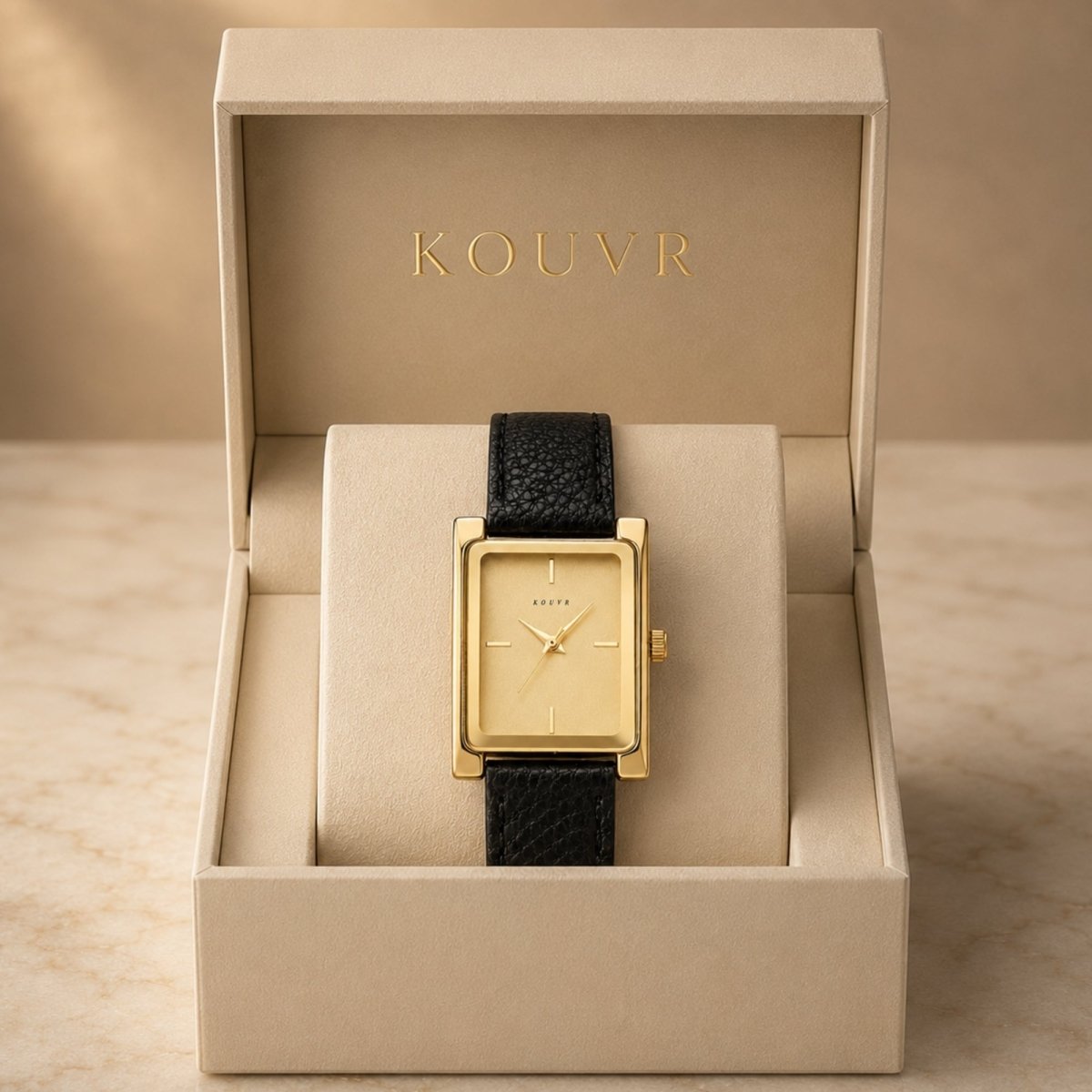 Kouvr women's vintage rectangular gold watch with black leather strap displayed inside a premium beige luxury presentation box.
 