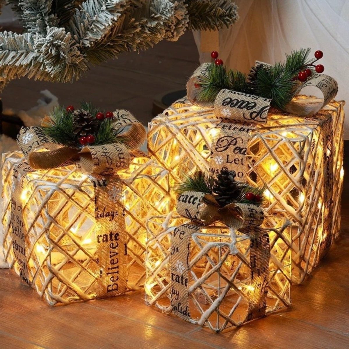 A close-up view of the Kouvr set of three woven Christmas gift boxes, highlighting the textured rattan, burlap ribbon, and warm internal LED lights.