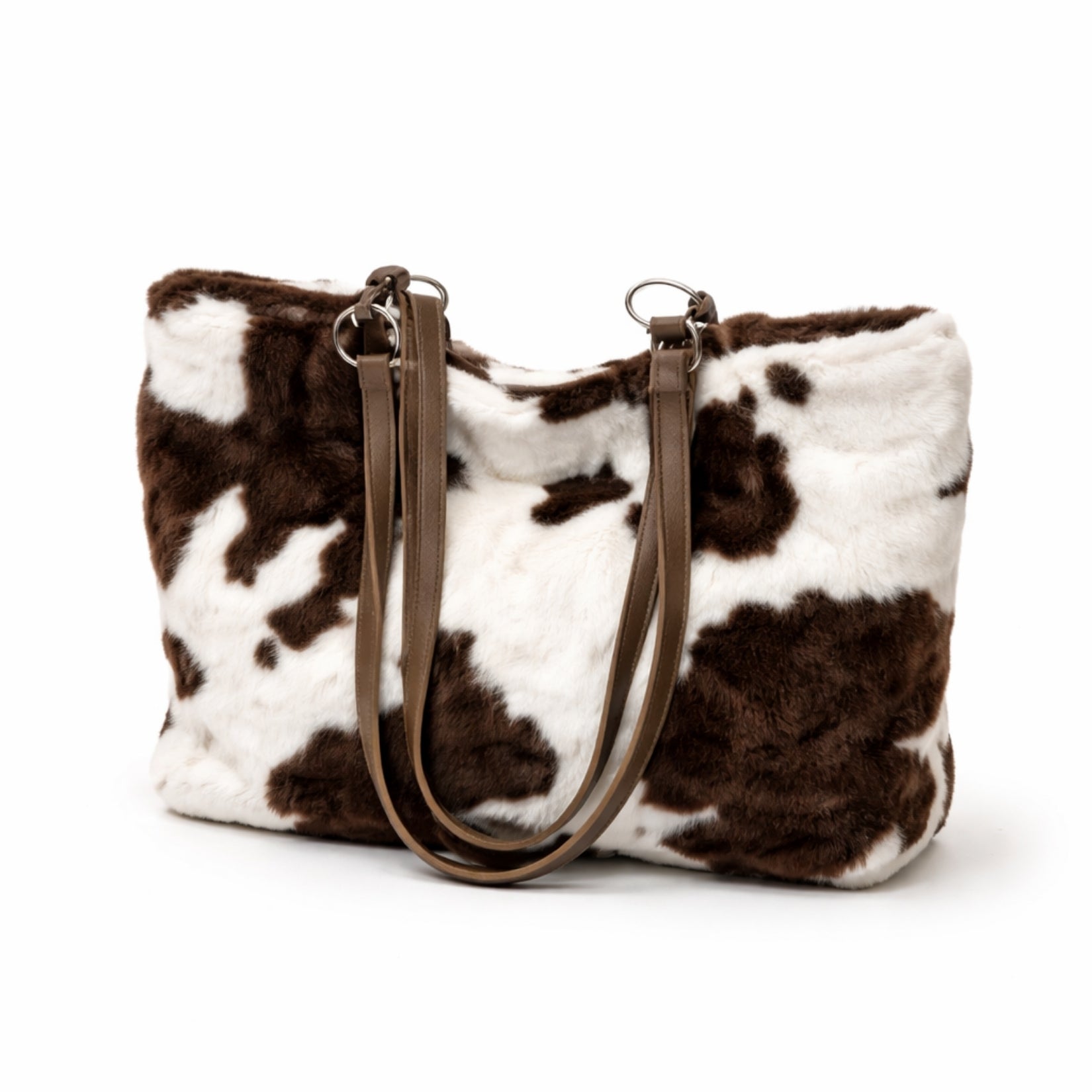 The Kouvr Xiara large faux fur tote bag in a brown and white cow print with vegan leather straps, shown on a white background.