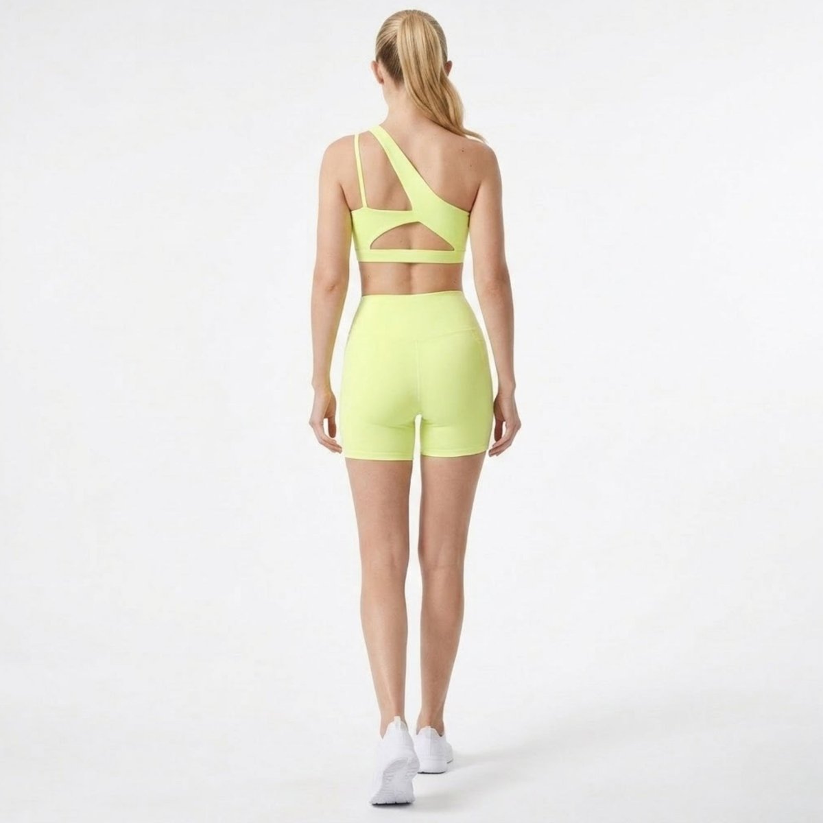 Back view of Kouvr  yellow activewear set showcasing strappy back cutout details on sports bra and fitted biker shorts